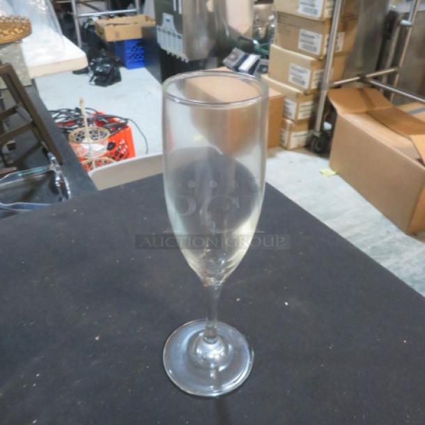 Clear glass champagne flute, model 11XBID, in used condition. No visible markings or damage. Standard size and shape.