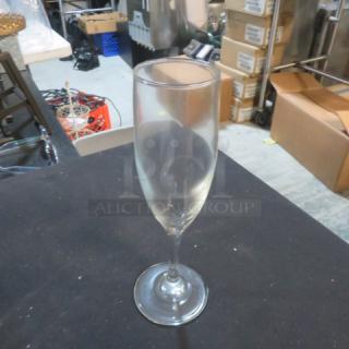 Clear glass champagne flute, model 11XBID, in used condition. No visible markings or damage. Standard size and shape.