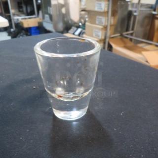 Clear glass shot glass, model 10XBID, in good condition. Features a smooth surface and a slightly flared rim.