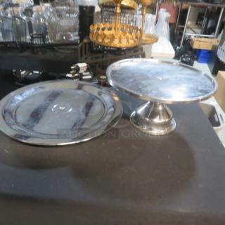 Assorted stainless steel display stands; includes one flat and one elevated stand. Shiny finish, good condition.