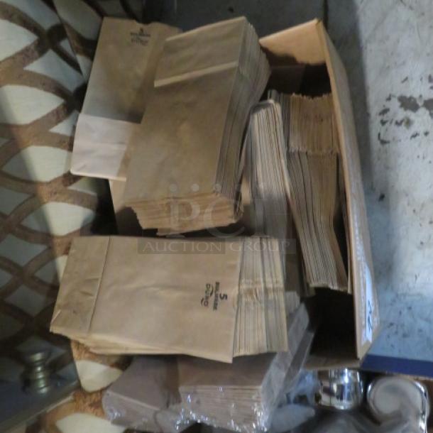 A lot of stacked brown paper bags in a box, showing various sizes, with a printed logo and small "S" markings.