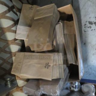 A lot of stacked brown paper bags in a box, showing various sizes, with a printed logo and small "S" markings.