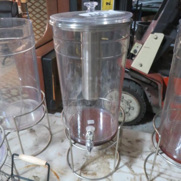 Clear beverage dispenser with metal stand and lid, featuring a spigot for easy pouring. Well-maintained condition.