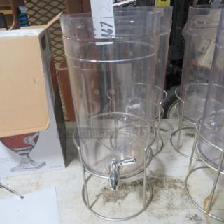 Transparent beverage dispenser with a chrome spigot, no lid. Supported by a metal stand. Model 2XBID.