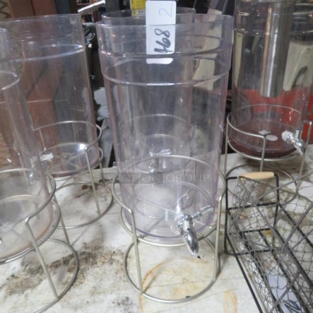 Clear plastic beverage dispenser with metal stand, missing lid. Appears in used condition. Tag reads "168 2".