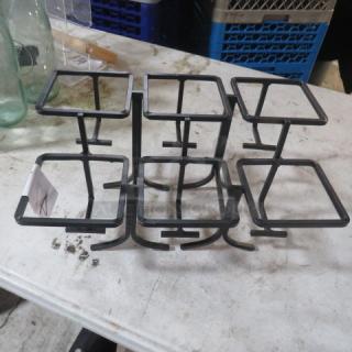 Black metal buffet display stand with six square platforms, sturdy design, minor wear. Ideal for catering or events.