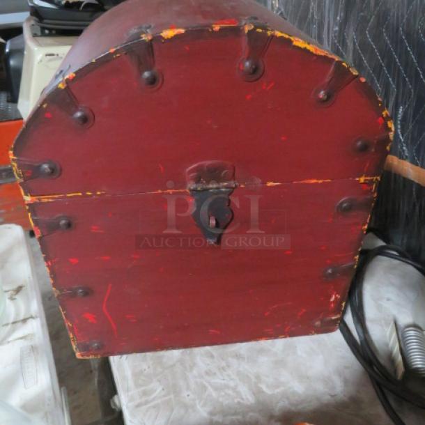 Red antique chest with rounded top, metal hardware, and visible wear. Distressed finish highlights age and character.