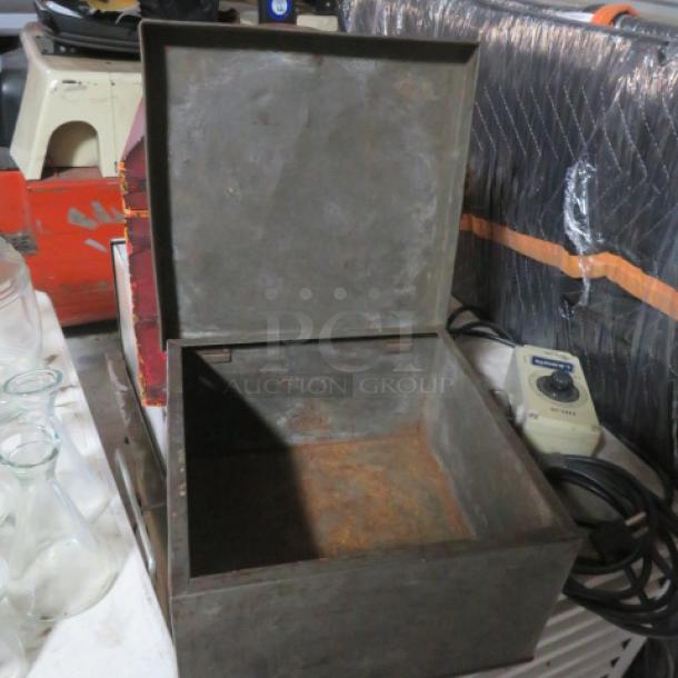 Open metal box with visible rust, surrounded by assorted glass bottles and electrical equipment. Box in fair condition.