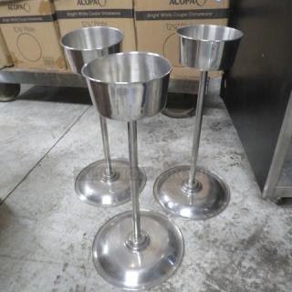 Three stainless steel champagne/wine bottle holders with pedestal bases. Sturdy and polished, suitable for elegant displays.