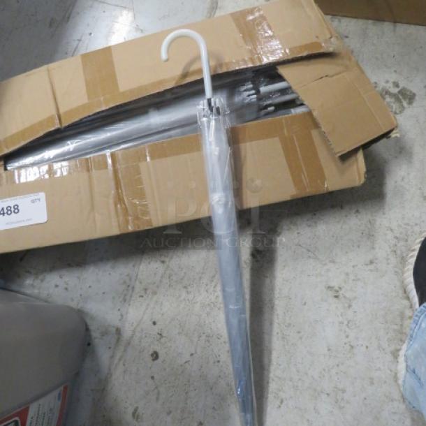 A case of new clear umbrellas in an open cardboard box, each with white handles, pristine condition, ready for use.