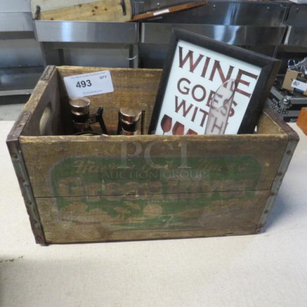 Vintage wooden crate with "Green River" branding, containing assorted decor items, including wine-themed framed art.