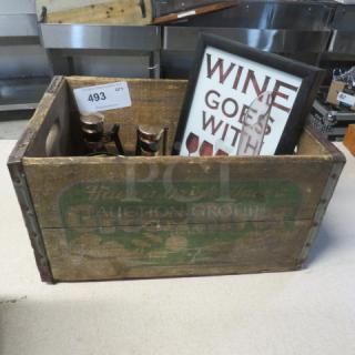 Vintage wooden crate with "Green River" branding, containing assorted decor items, including wine-themed framed art.