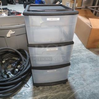 Three-drawer plastic organizer on casters, transparent drawers, labeled for storage, in good condition.