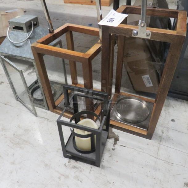 Assorted lanterns, varying sizes and materials, including metal and wood frames. Includes candles, showing moderate wear.