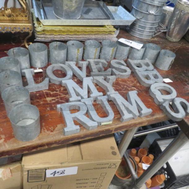 Galvanized metal letters and holders, spelling "LOVE MY RUM," on a wooden table; good condition.