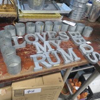 Galvanized metal letters and holders, spelling "LOVE MY RUM," on a wooden table; good condition.