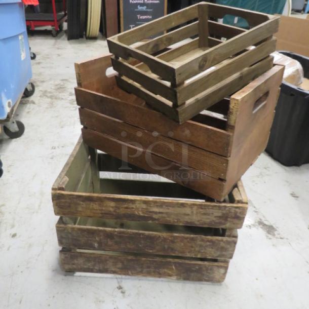 Three assorted wooden decor boxes in rustic condition, varying sizes, utilitarian handles, stacked on a concrete floor.