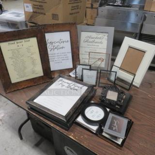 Assorted decor lot with framed signs and empty photo frames on a wooden table. Includes wedding and event signage. Good condition.