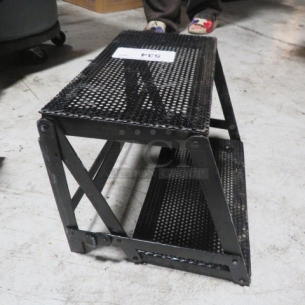 Black metal 2-tier display stand, durable mesh design, slight wear; auction tag reads "2XBID, 534."