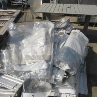 Rolled event tent with transparent and white fabric, metal framework visible. Appears used, suitable for outdoor events.