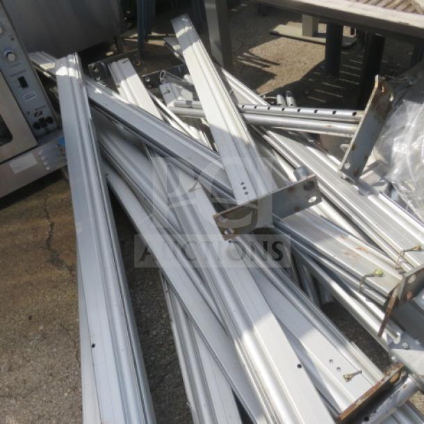 Stack of aluminum frame components for semi-permanent commercial event tent, showing slight wear, no visible markings.