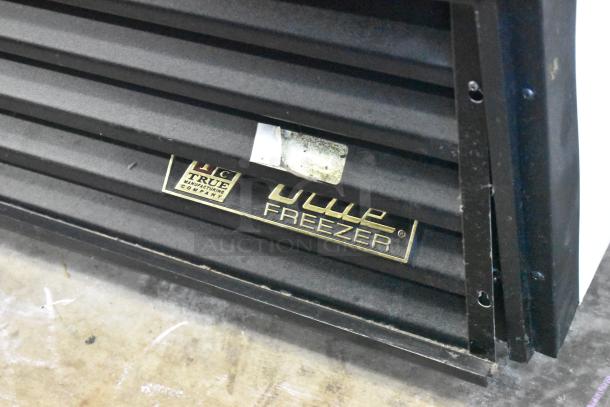 True GDM-72F-LD commercial freezer label, showing brand and "freezer" text on black metal surface.