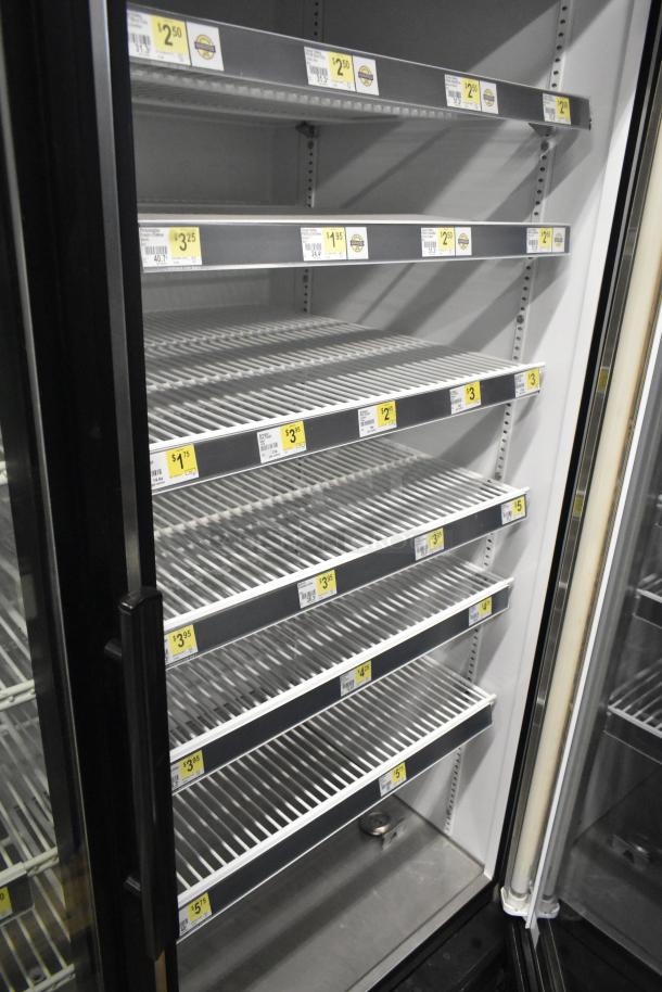 True GDM-49 commercial 2-door reach-in cooler merchandiser, empty shelves, price labels visible, 115V, 1 phase.