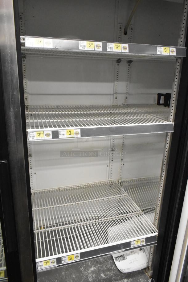 True GDM-72 commercial cooler, 3-door, 115 volts, 1 phase. Shelves with product price labels visible, good condition.