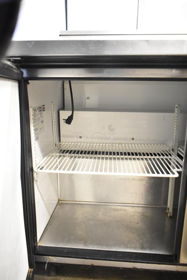 True TSSU-48-12 commercial sandwich salad prep table interior, metal shelf, and power cord. Model label inside.