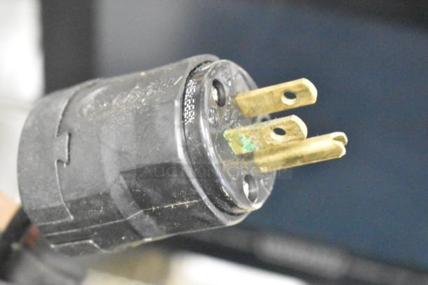 Close-up of a black and gold electrical plug with three prongs.