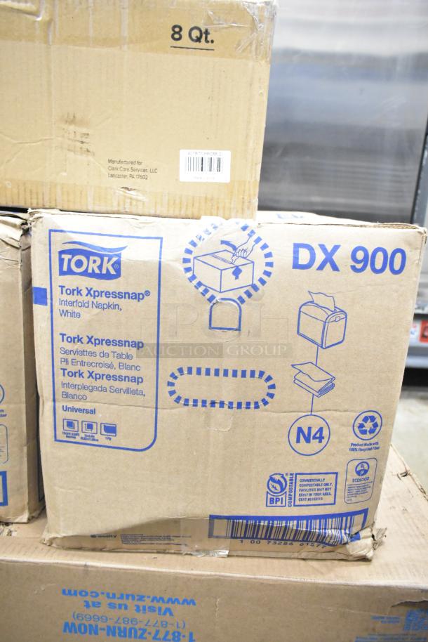 Cardboard boxes of Tork DX900 Xpressnap white interfold napkins, featuring branding and product details.
