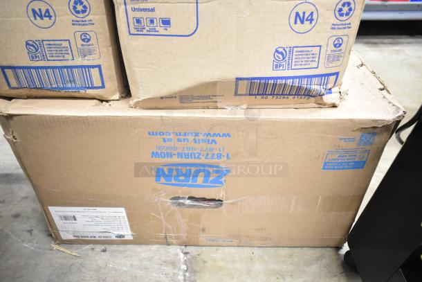 Cardboard boxes of Zurn Z1996-24 Mop Basin Grey and Tork DX900 Napkins stacked; minor wear visible.