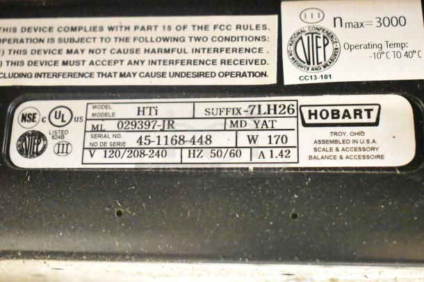 2017 Hobart HTi-7LH26 metal food portioning scale label showing model, voltage, serial number, and certifications. No power cord.