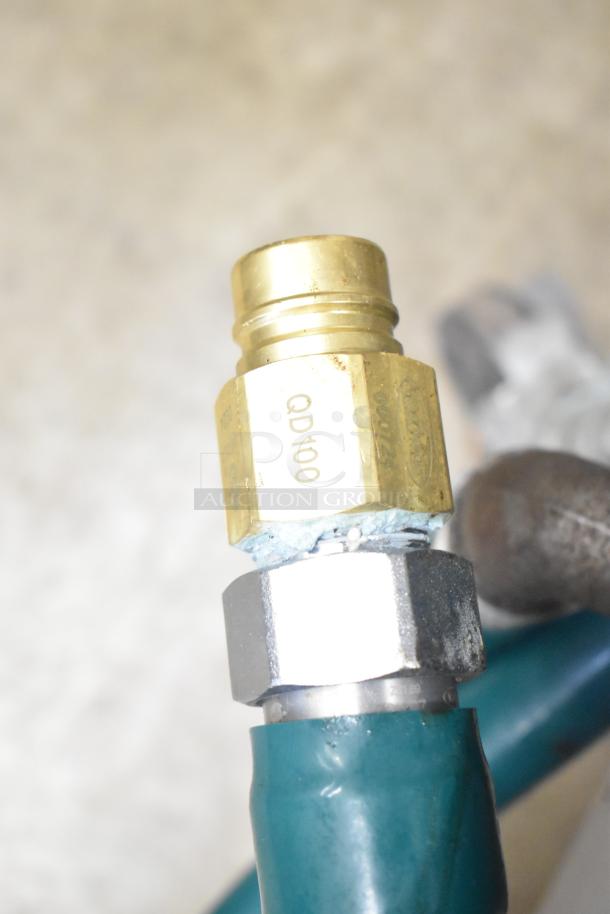 Close-up of a brass fitting labeled "QD100" on a gas line for a Motak commercial stock pot range.