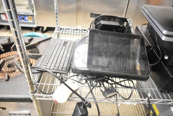 10 items including cash drawers and POS monitors on a metal shelf. Includes a keyboard and tangled cables. Mixed condition.
