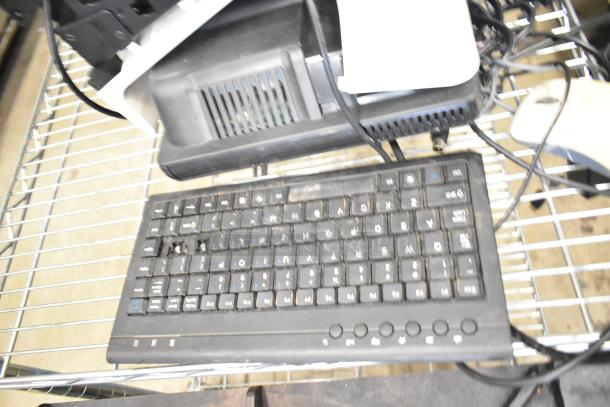 Keyboard and electronics on a wire rack. Includes POS devices and cables. Condition appears worn, suitable for parts or repair.