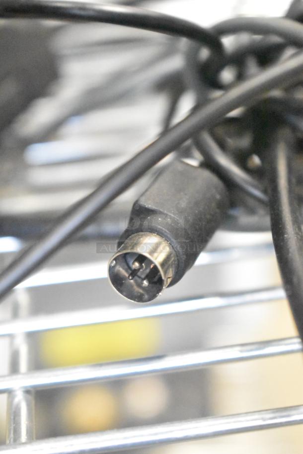Close-up of a black electronic cable with a pin connector, part of auction lot including cash drawers and POS monitors.