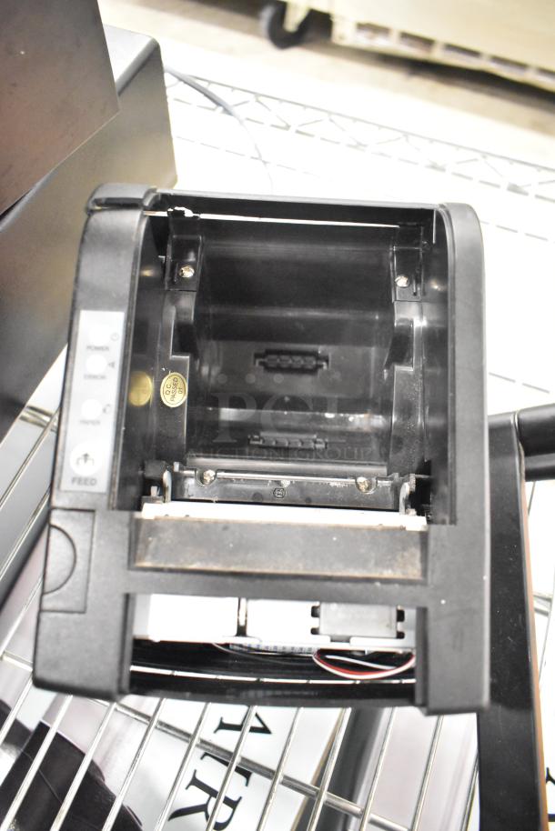 Open cash drawer showing interior components, featuring power and feed buttons. Quality control sticker visible.