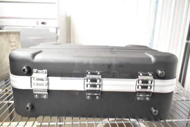 Black Rae hard case with silver latches, textured surface, and metal trim. Appears in good condition, sturdy construction.
