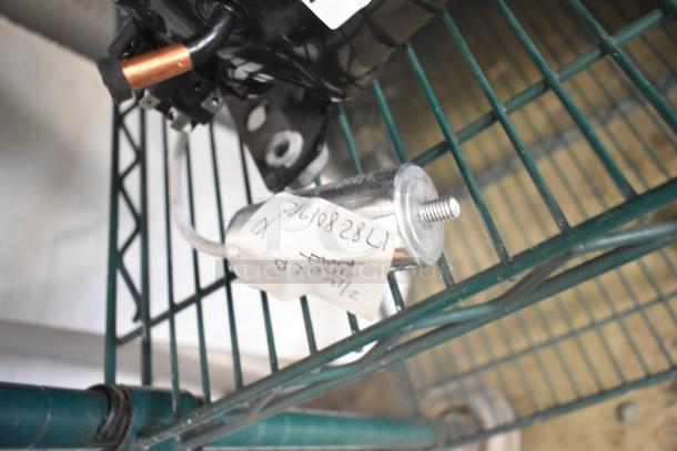 Cubigel NUT55NR Compressor, 151-127 Volts, 1 Phase. Displayed on a shelf. Visible handwritten tag for identification.