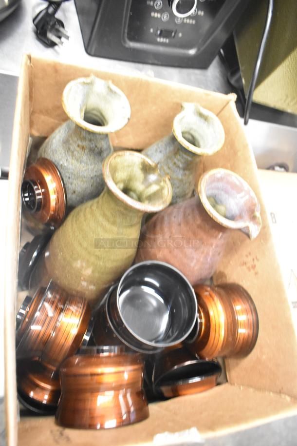 Box of assorted items including ceramic vases, bowls, and poly trays in various colors and finishes.