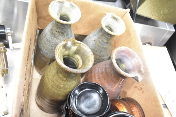 Lot of ceramic vases and bowls in cardboard box; assorted colors, good condition. Includes poly trays, various designs.