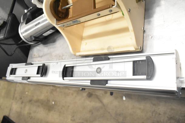 Antree meat grinder attachment, Aicok HM833 hand blender, and two additional items on a metal table, moderate wear.