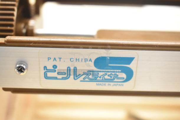 Label reading "Pat. Chiba" and "Made in Japan" on metal surface of appliance. Features part of a mechanical structure.