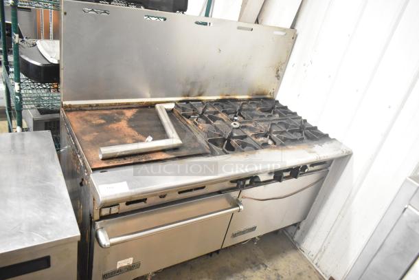 American Range commercial gas 6-burner range with flat top griddle, 2 ovens, and backsplash. Visible wear, stainless steel.