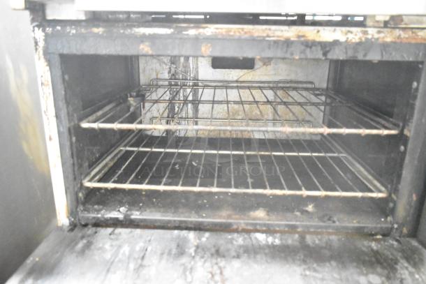 American Range commercial gas oven interior showing two metal racks, signs of use on surfaces.