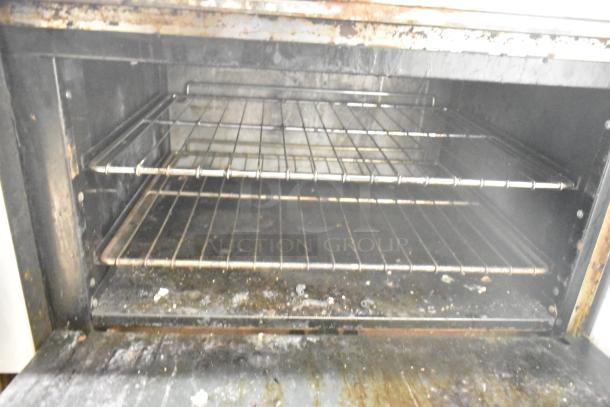 American Range commercial gas oven interior, showing two wire racks, signs of use, and slight wear.