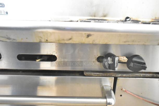 American Range commercial gas 6-burner with flat top griddle, dual ovens, controls visible, some wear and residue.