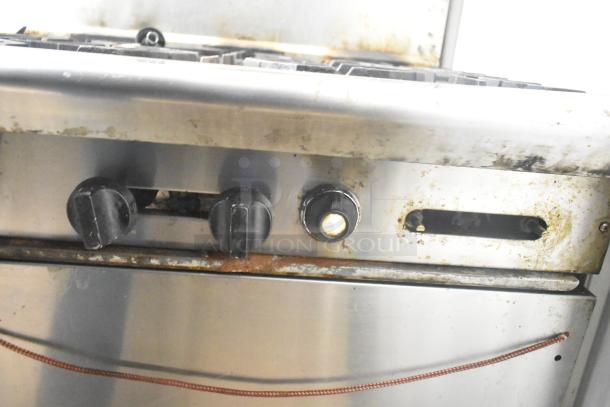 American Range commercial gas-powered 6-burner stove with flat top griddle, 2 ovens, and backsplash. Visible wear and rust.