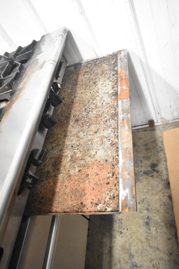 American Range commercial gas 6-burner range with flat top griddle, two ovens, and back splash; shows signs of wear.